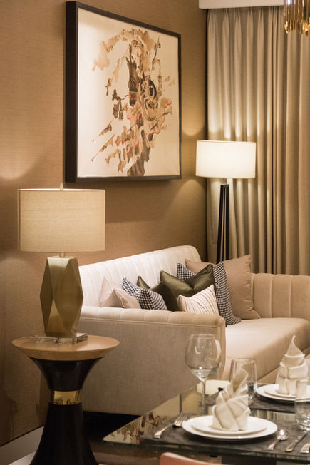 Elegant living room featuring a sofa with decorative pillows, table lamps, and floor-to-ceiling curtains.