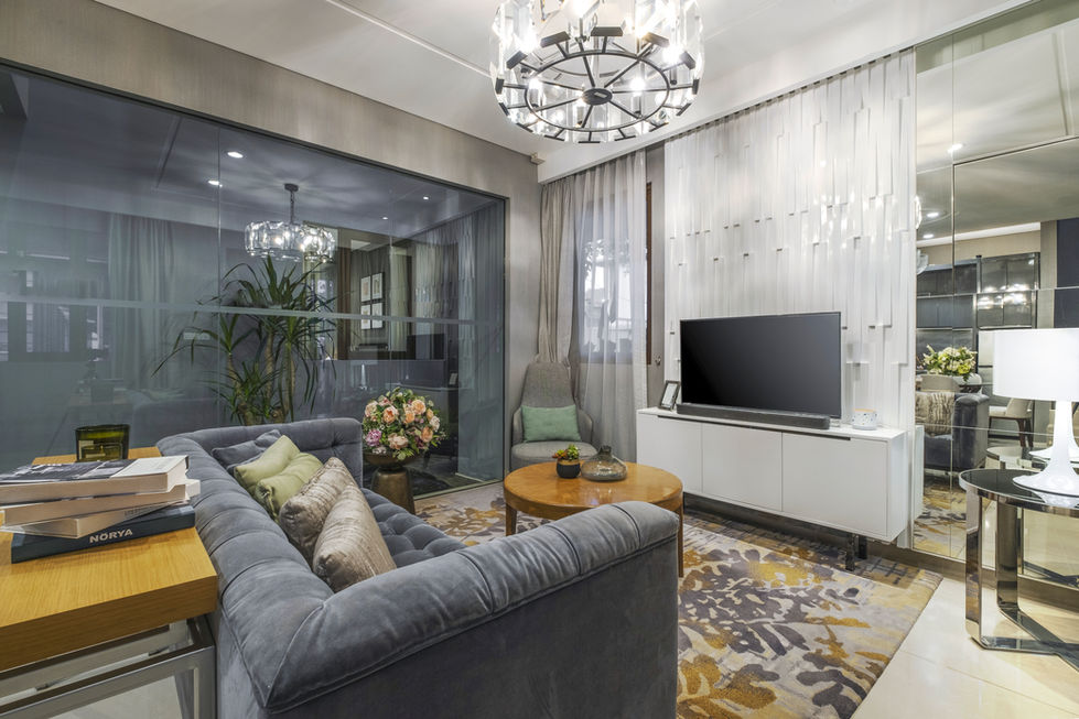 Living room setting focusing on a grey sofa, a sleek white TV console, and a large window looking into a landscaped indoor garden.