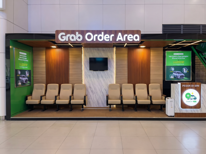 Modern Grab Order Area booth with rows of beige waiting chairs, a service counter, and promotional green signage against wood-slat panel walls.