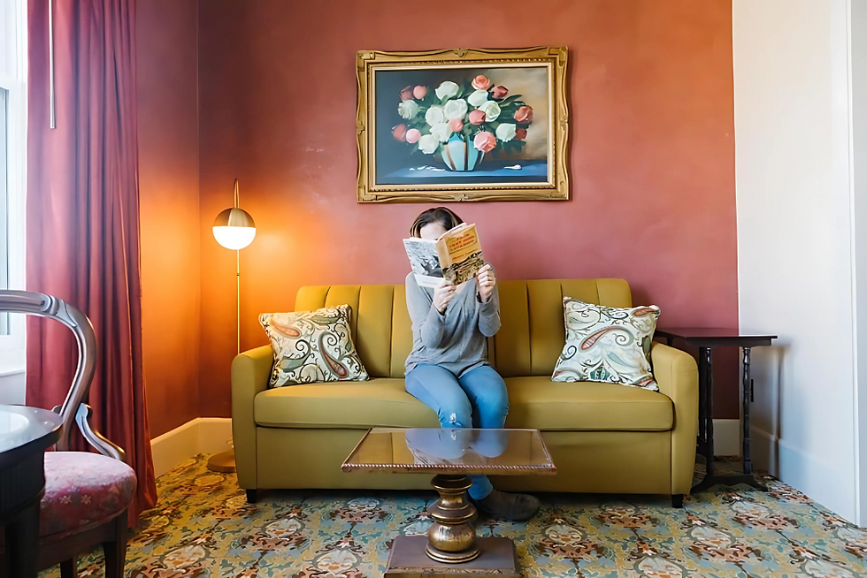 Guest enjoying a book on a yellow sofa in a Belvada Hotel suite with stylish decor