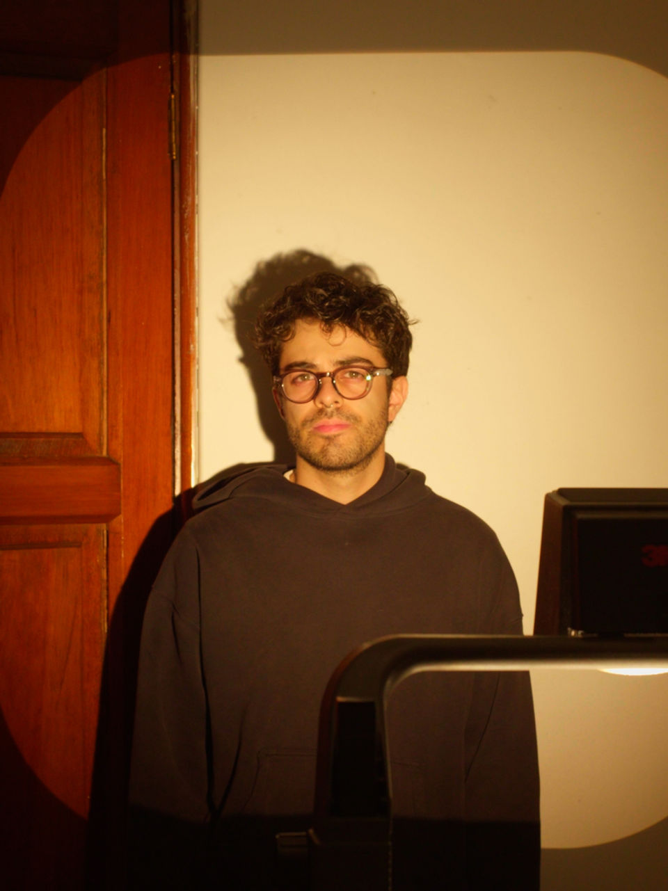 Atherion, creador de video, posando entre luz cálida y sombras con esa vibra de hacer cine para la pequeña pantalla, aunque el detrás de cámaras sea grabar feo y editar bonito.