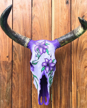 A cow skull painted in violet with flowers.