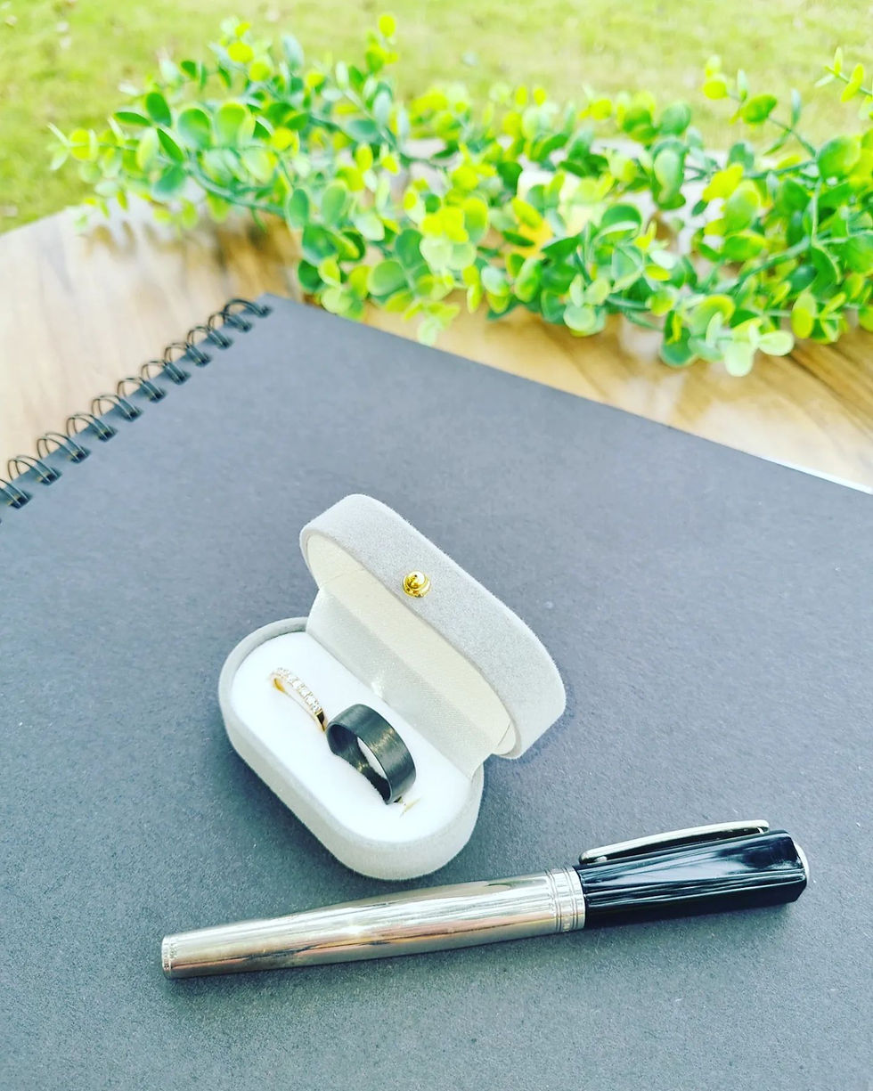 Wedding rings, pen and wedding paperwork folder