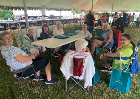 A group of older adults sitting around a picnic table.