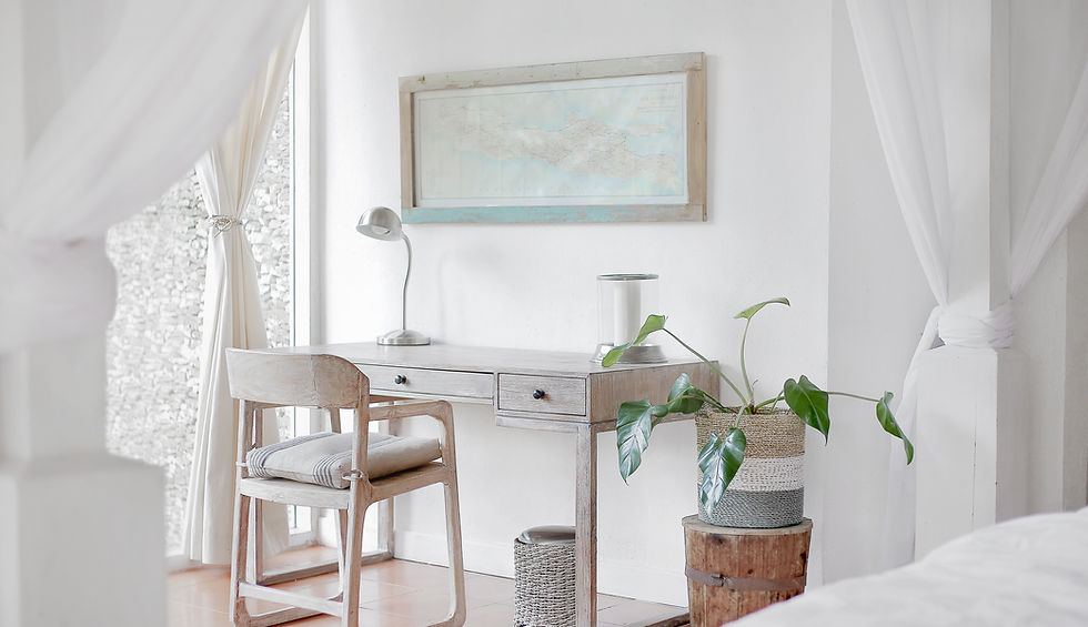 na imagem contem: uma cadeira, uma mesa, um cesto com uma planta dentro. uma sala do tipo escritorio com um mesanino com uma luminaria e um quadro a frente.