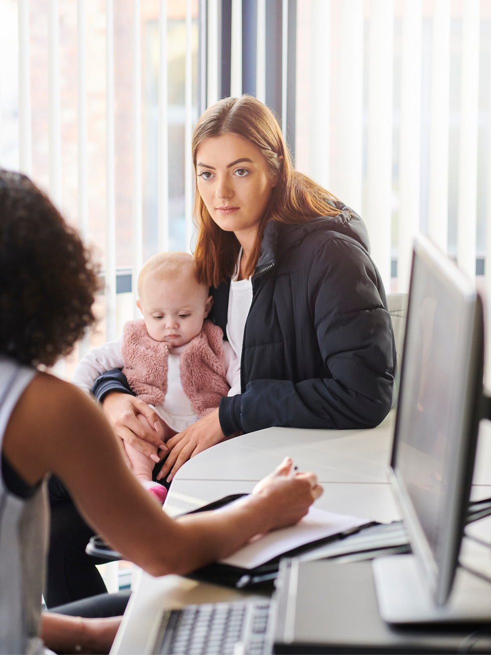 Alt Text: A mother holds her baby during a perinatal mental health therapy session with a healthcare professional, illustrating postpartum support.