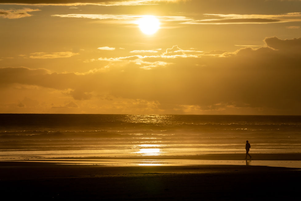 a person walking on a beach at sunset