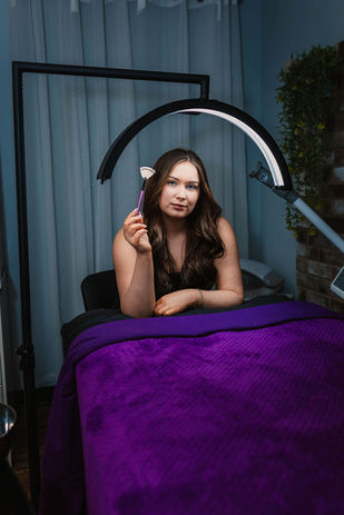 Woman holding tweezers on a purple treatment bed