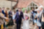 Bride and groom walking through confetti tunnel at Priston Mill wedding
