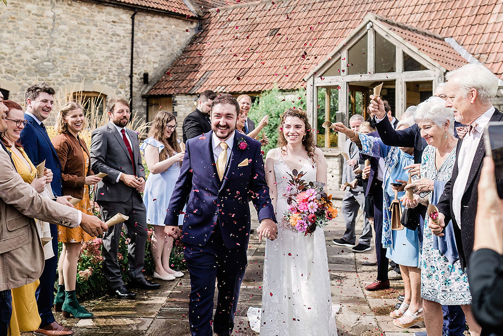 Bride and groom walking through confetti tunnel at Priston Mill wedding