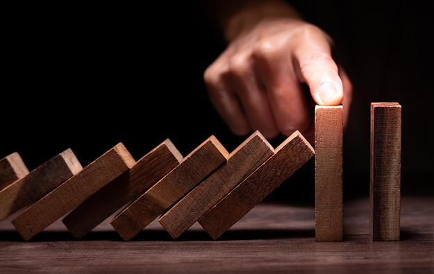 insurance with hands protect domino. Businessman hands stop dominoes falling in business c