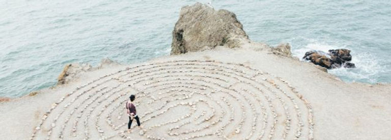 a person walking through a labyrinth in the sand as they contemplate