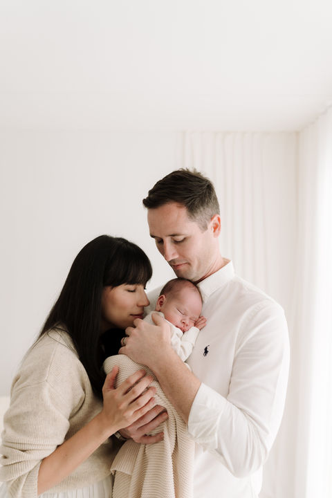young couple and their baby taken by newborn photographer, sarah taylor