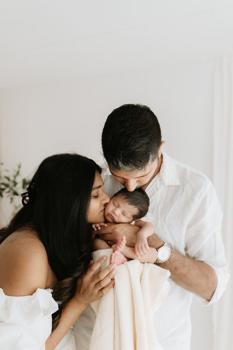 couple holding and kissing their baby