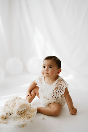1 year old baby next to cake