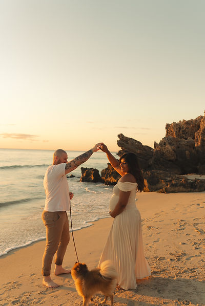 a couple with their dog during a maternity photoshoot at the beach