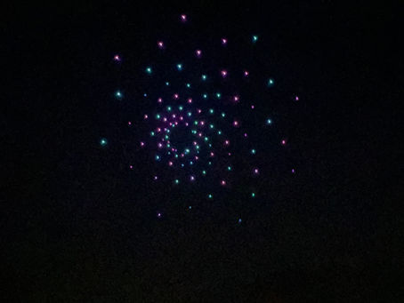 drones forming a colorful starburst/flower (pink/teal) — corporate event entertainment
