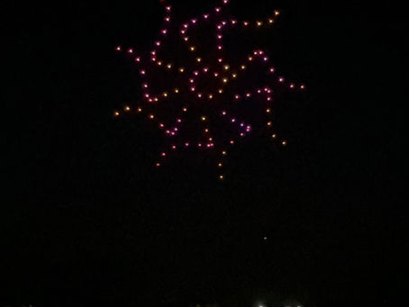drones forming a colorful starburst/flower (pink/yellow) — indoor event entertainment