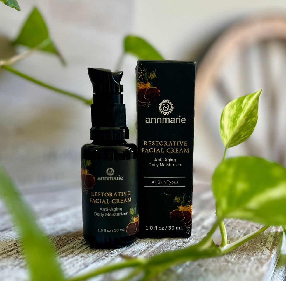 Annemarie Restorative Facial Cream glass bottle with pump and packaging displayed on whitewashed wood with greenery.