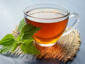 Glass Cup of Tea with a tea leaf on a burlap coaster.