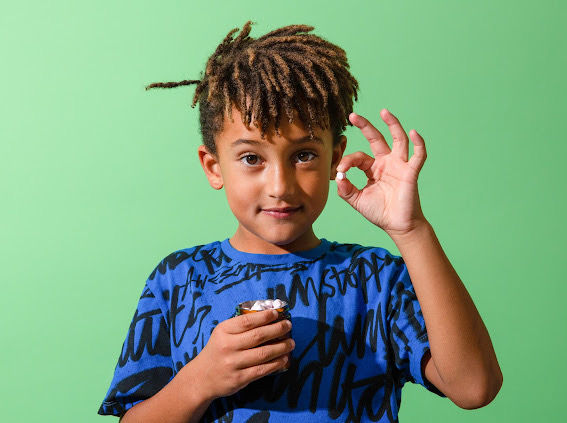 Thumbnail: Little boy holding a jar of Canary Toothpaste Tablets in one hand and showing one toothpaste tablet in the other hand.