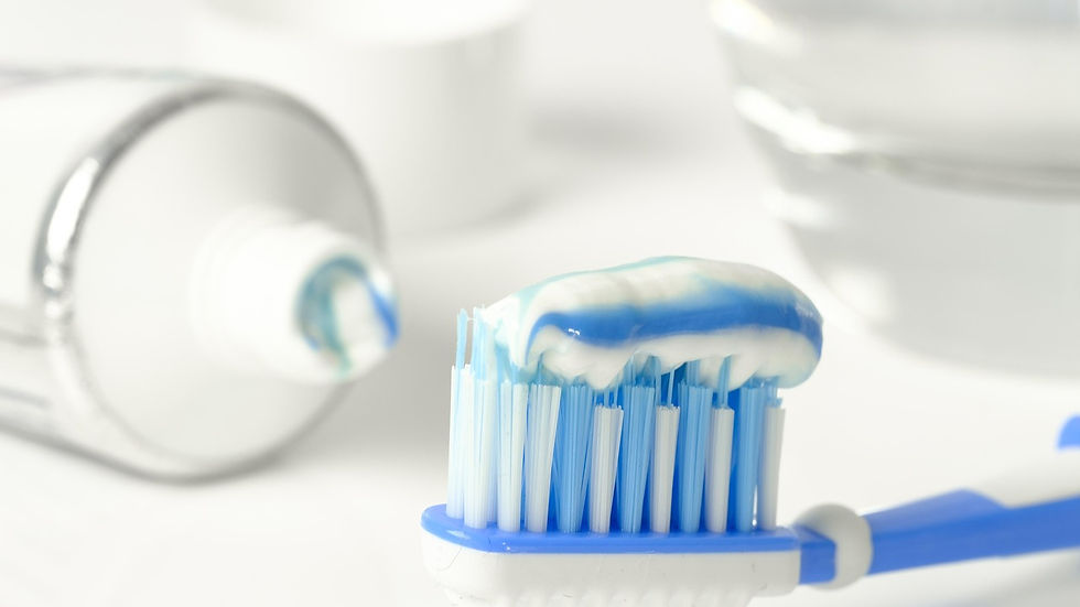 Toothpaste tube with blue and white toothpaste on a toothbrush