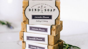 Bend Soap Co. Lavender Blossom Goat Milk Bar Soaps with logo labels stacked and displayed with lavender flowers on white marble.