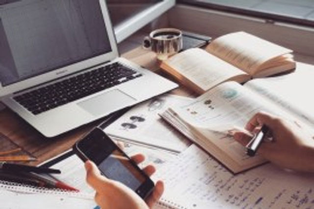 student at desk studying with books and technology