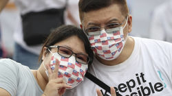 Taiwanese couple wearing face masks with small Taiwanese flags on them, smiling at the camera.