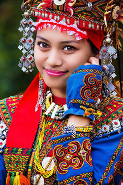 Girl smiling, wearing colourful Austronesian clothing and headwear.
