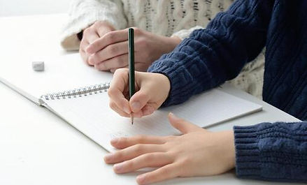ノートに鉛筆で書く生徒の手元と見守る社会人プロ講師