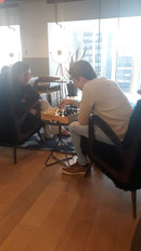 Duas pessoas jogando xadrez enquanto conversam sobre estratégias em uma sala corporativa, simbolizando planejamento e decisões de vendas.