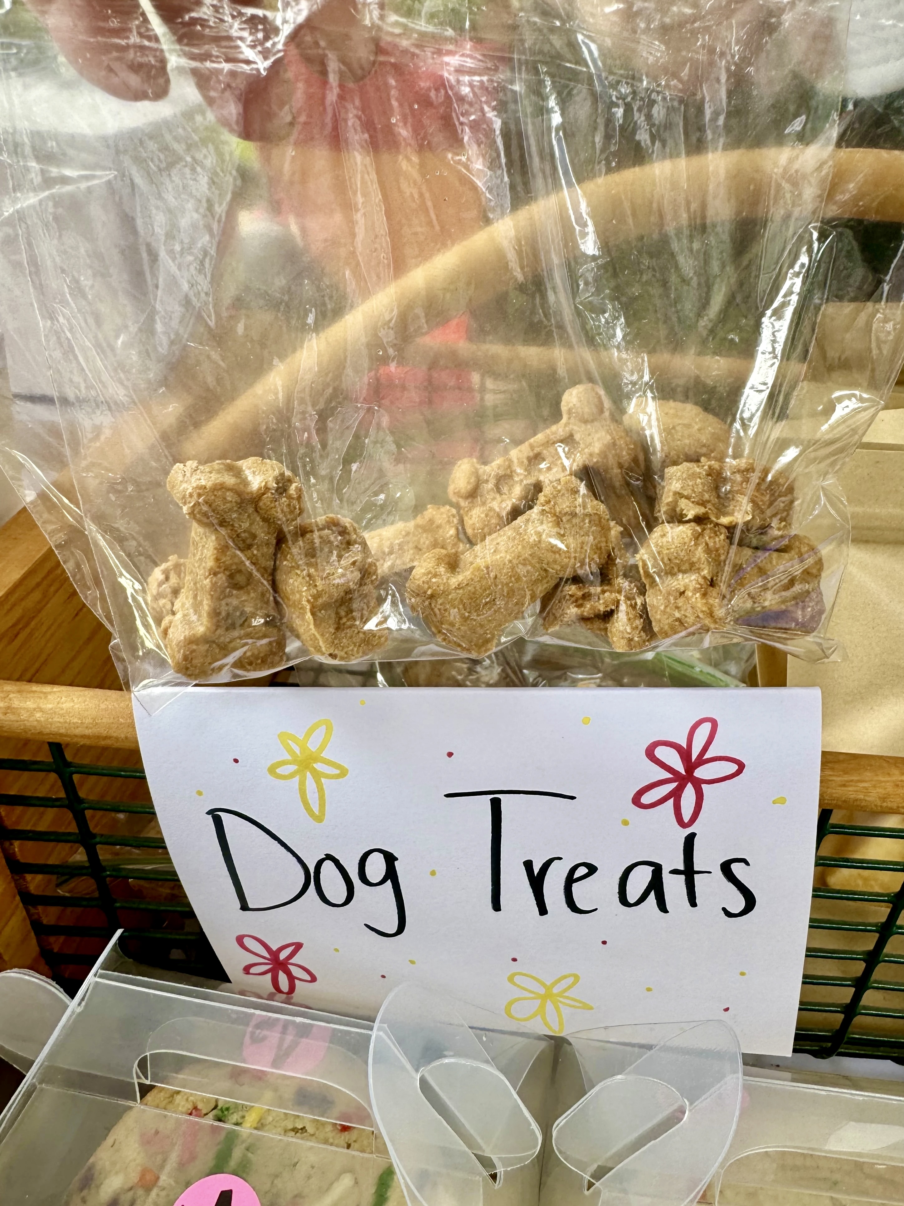 Clear bag of dog treats on a shelf, with a hand-lettered Dog Treats sign decorated with flowers.