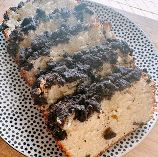 Slices of crumb cake with dark topping on a white plate with black dots. Wood table and tile floor in background. Warm, inviting mood.
