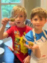 two boys hold up golden snitch truffles with wings on them at harry potter baking camp in birmingham