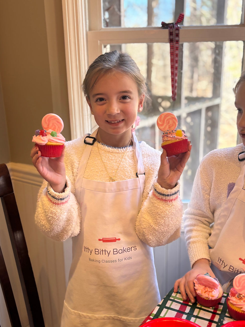 girl holds two pink cupcaks