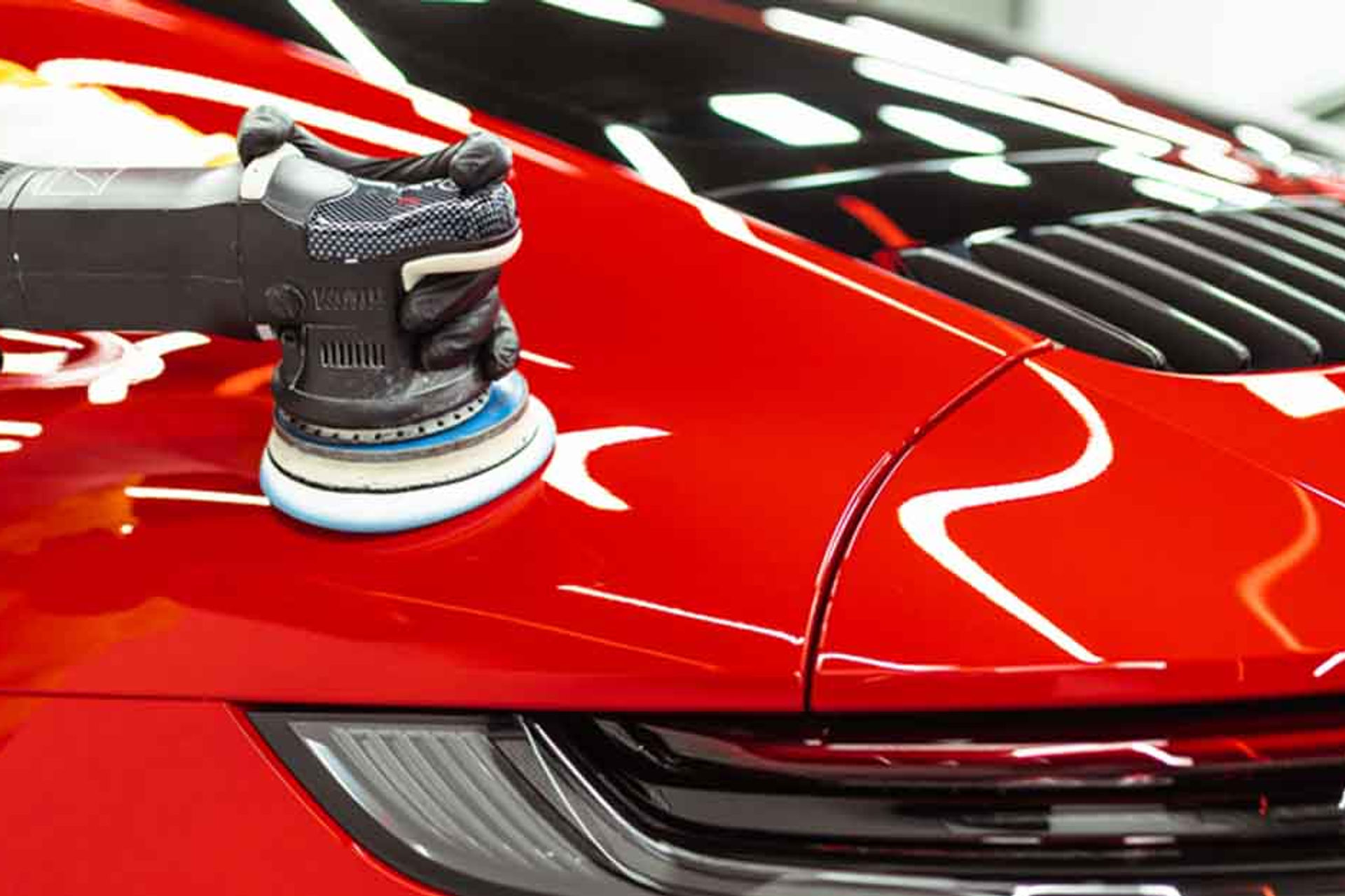 Machine polishing a car panel under workshop lighting at MintGroom