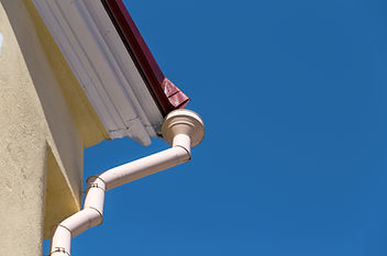 White gutter system on a house against a blue sky