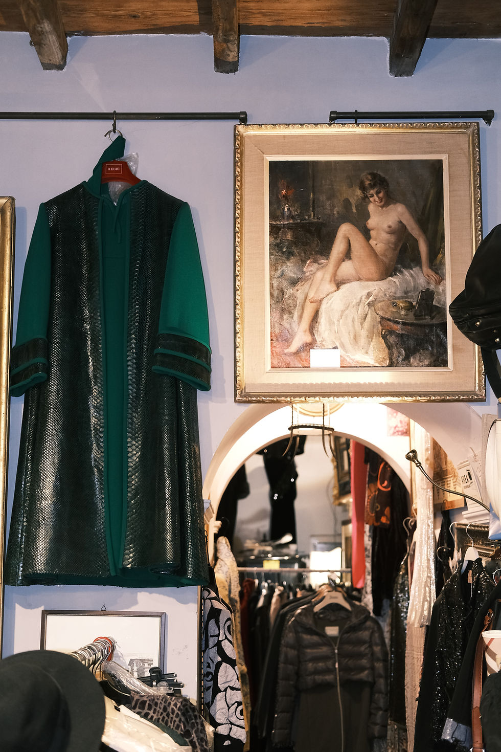 Lovely shop "Ciao Vintage" filled with antique and designer shoes and accessories and clothes. On wall a portrait of a nude woman hangs next to a deep green jacket.