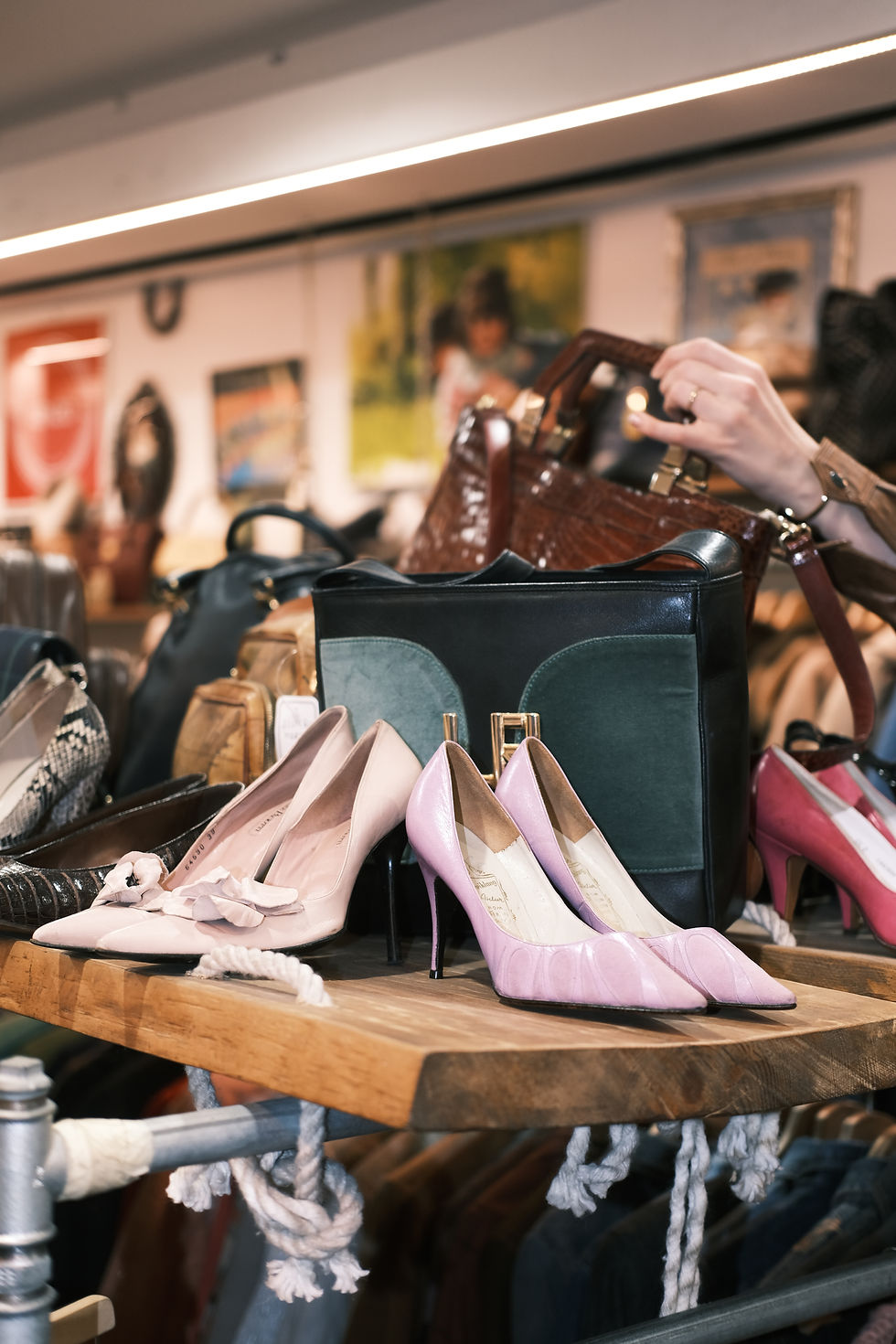 Two pair of vintage shoes / high heals in lavender on wooden shelf, in front of woman's hand reaching for purse.
