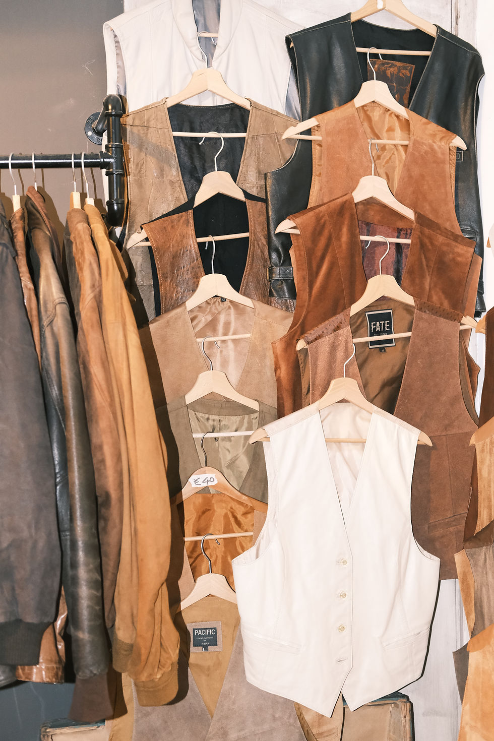 Vintage leather vests hanging from wall.