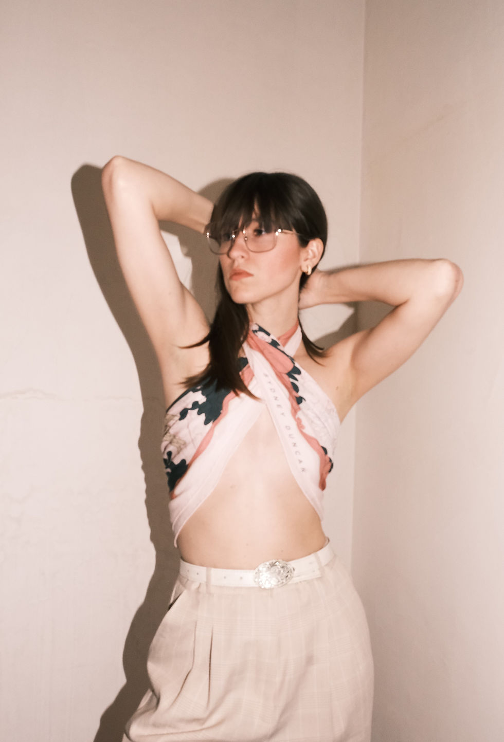 Sydney posing with arms above her head wearing sexy y2k scarf sop with "Sydney Duncan" logo across the hem.
