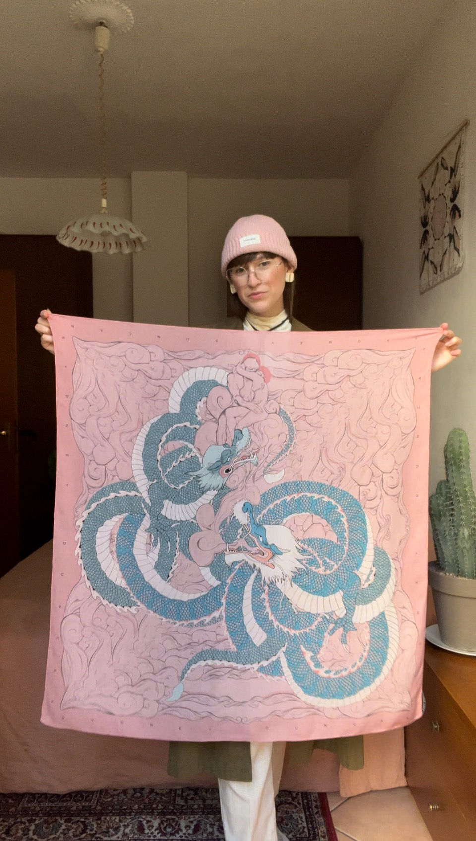 Sydney holding up a tencel scarf in a mauve pink color with a Japanese dragon print.