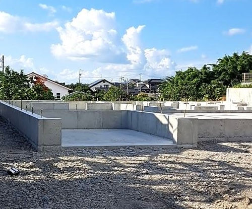 新築住宅の基礎部分。コンクリートがきれいに仕上がり、隣の家の景色とともに写っている。