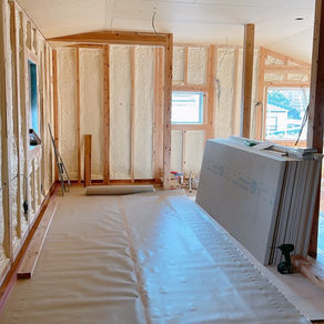 天井ボード貼りと床の養生が完了した木造住宅の室内。断熱材が施工された壁と、丁寧に養生された床が見える現場の様子。