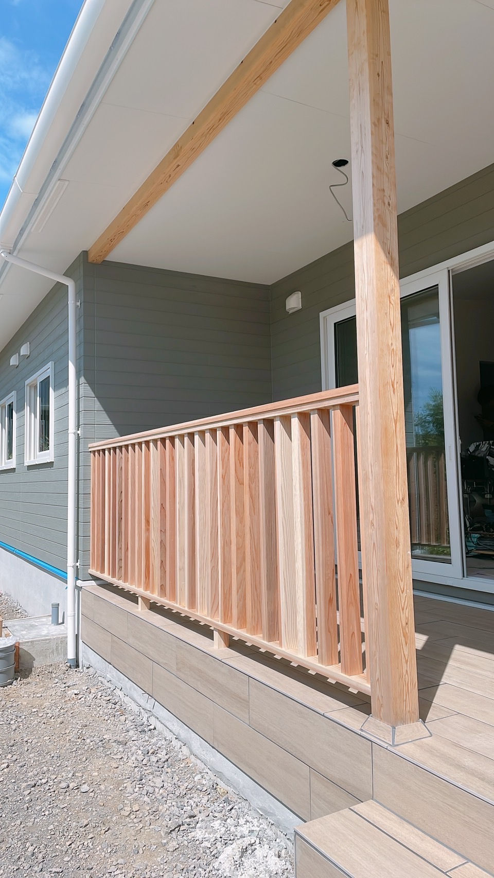 新築住宅のカバードポーチに取り付けられた木製フェンス。ナチュラルな木の質感が映える外観
