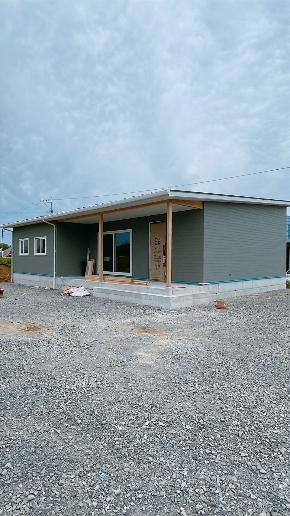 建築中の平屋住宅の外観。シンプルな片流れ屋根とウッドデッキ付きの玄関ポーチが特徴的。