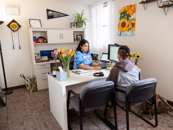 A college student sits across the desk from an academic advisor. 