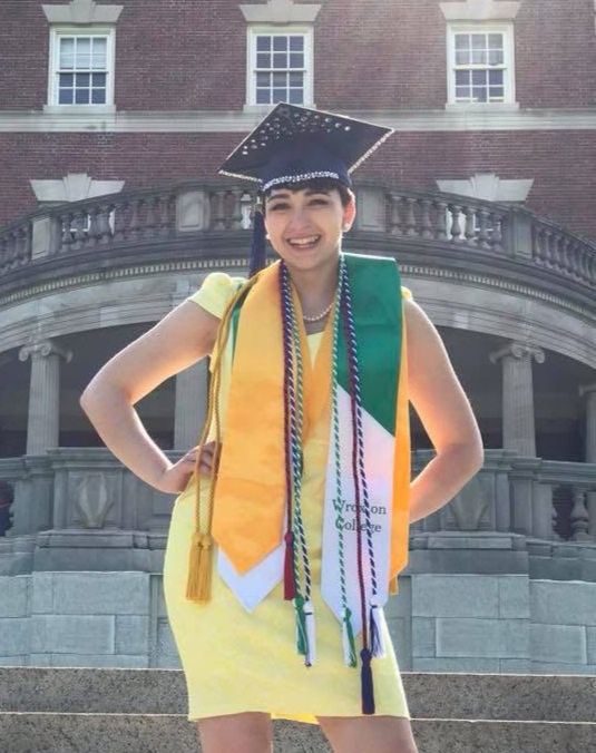 Sophia standing with her college graduation cords and stoles.