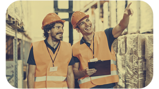 Two warehouse employees in safety vests and hard hats discussing logistics—example of employment types and payroll considerations for small business accounting and contractor vs employee classification.